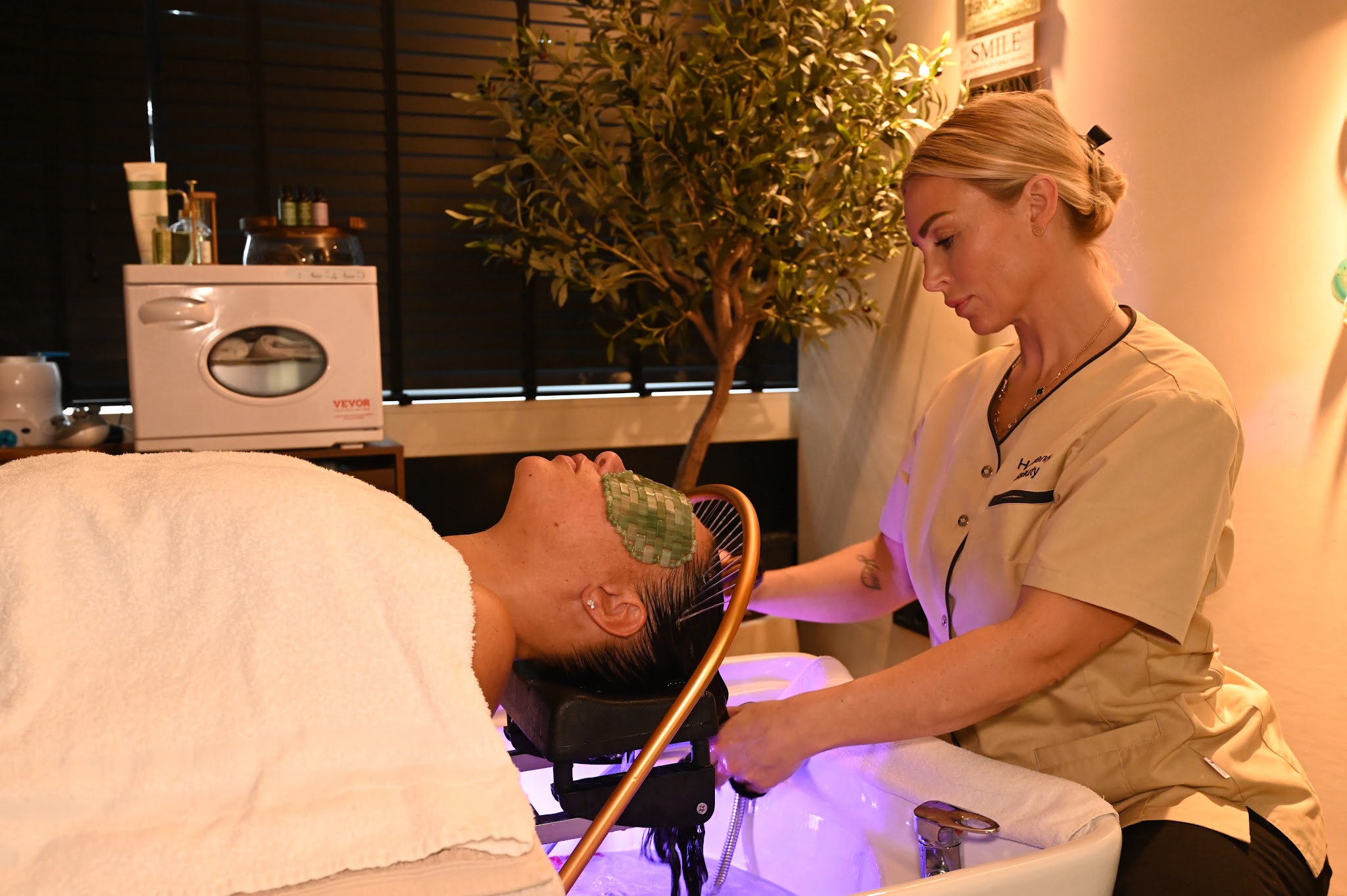 Een behandelaar brengt een gezichtsmasker aan bij een klant op de headspa-stoel